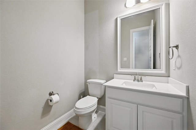 bathroom featuring toilet, vanity, and baseboards