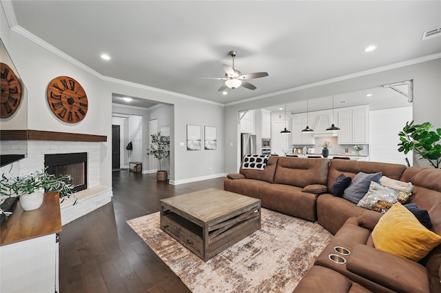 living room featuring a ceiling fan, dark wood finished floors, baseboards, recessed lighting, and a brick fireplace