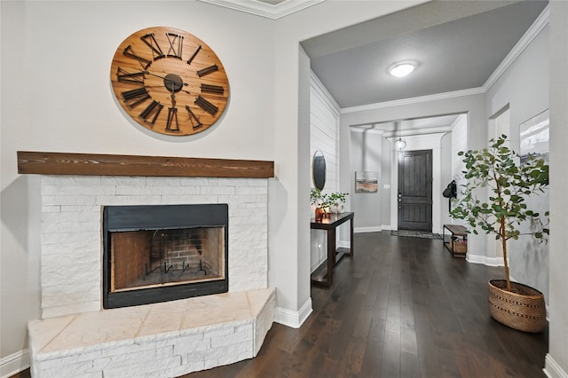 foyer entrance featuring wood finished floors, baseboards, ornamental molding, and a fireplace with raised hearth