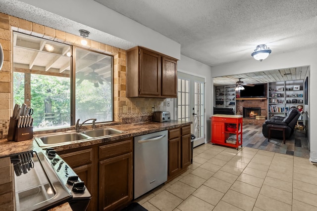 kitchen featuring stainless steel dishwasher, french doors, a sink, and a wealth of natural light