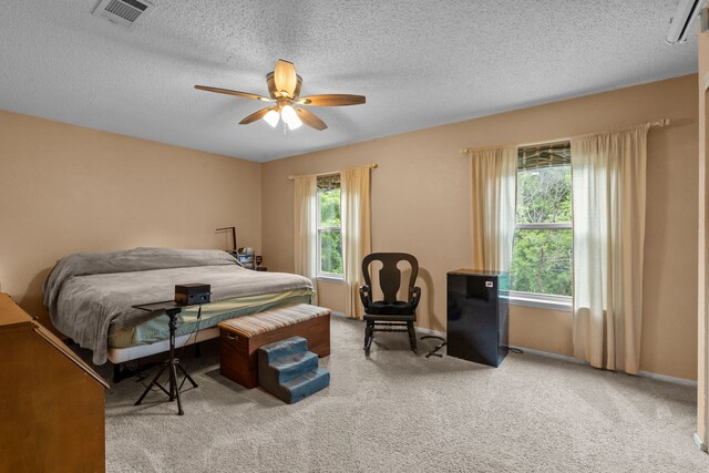 bedroom with a textured ceiling, ceiling fan, carpet floors, baseboards, and visible vents