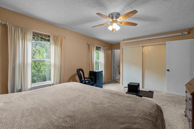 bedroom with carpet, a ceiling fan, a textured ceiling, and a closet