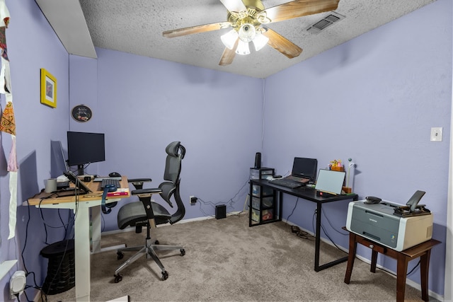 carpeted home office featuring a textured ceiling, visible vents, and a ceiling fan