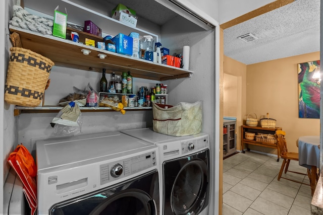 laundry area with washing machine and dryer, a textured ceiling, visible vents, and tile patterned floors