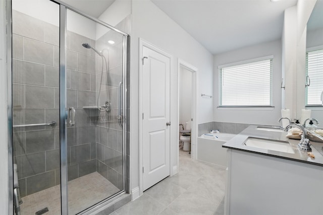 bathroom with tile patterned floors, a sink, double vanity, a stall shower, and toilet