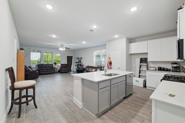kitchen with light countertops, stainless steel dishwasher, ceiling fan, and a sink