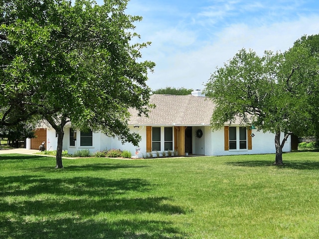 ranch-style home featuring a chimney, a shingled roof, a front yard, and an attached garage