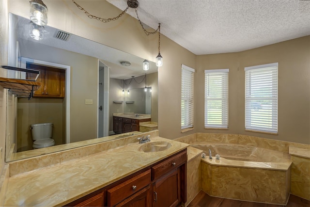 full bath featuring a textured ceiling, visible vents, a bath, wood finished floors, and vanity
