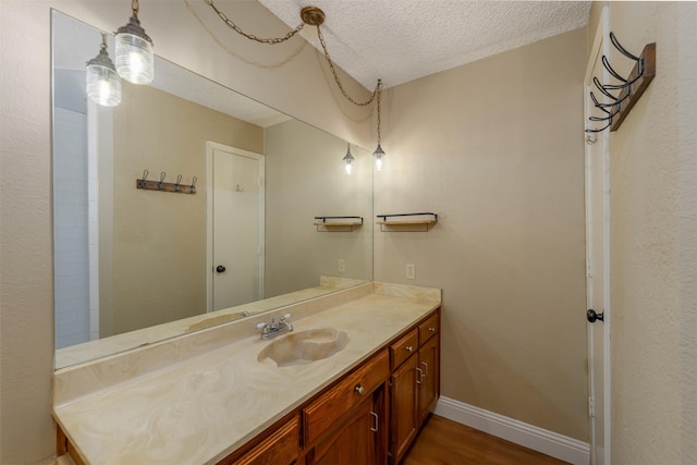 bathroom with baseboards, wood finished floors, a textured ceiling, and vanity
