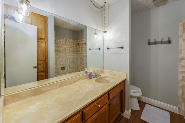 bathroom featuring vanity, toilet, baseboards, walk in shower, and wood finished floors