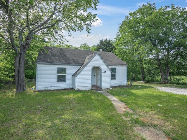 view of front of property with a shingled roof, a front lawn, and fence