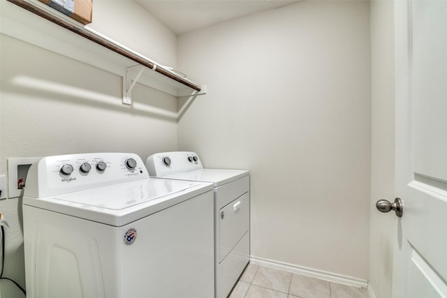laundry area featuring baseboards, washer and clothes dryer, laundry area, and light tile patterned floors
