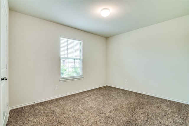 carpeted empty room featuring baseboards