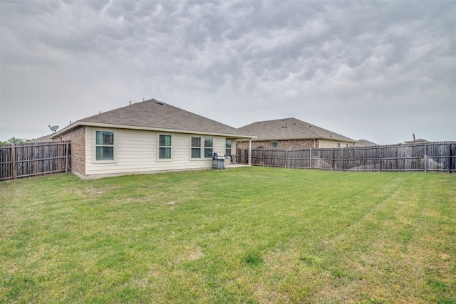 rear view of property with a fenced backyard and a lawn