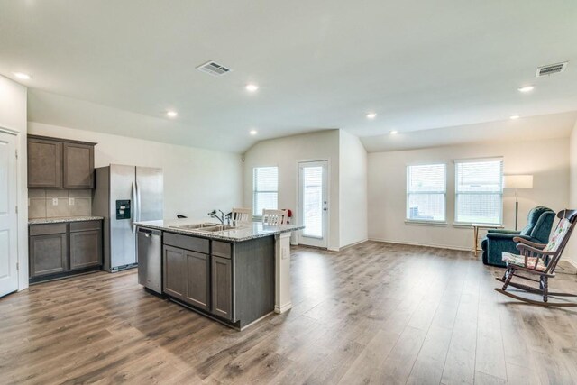 kitchen with a sink, open floor plan, visible vents, wood finished floors, and appliances with stainless steel finishes