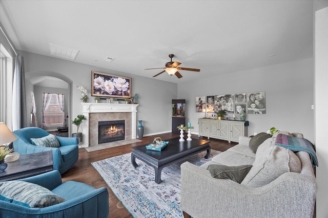 living area featuring arched walkways, visible vents, wood finished floors, ceiling fan, and a fireplace