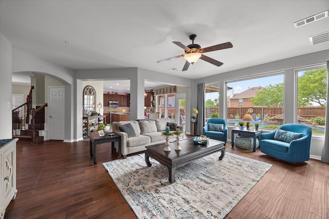 living area featuring dark wood-style flooring, a ceiling fan, stairs, and visible vents