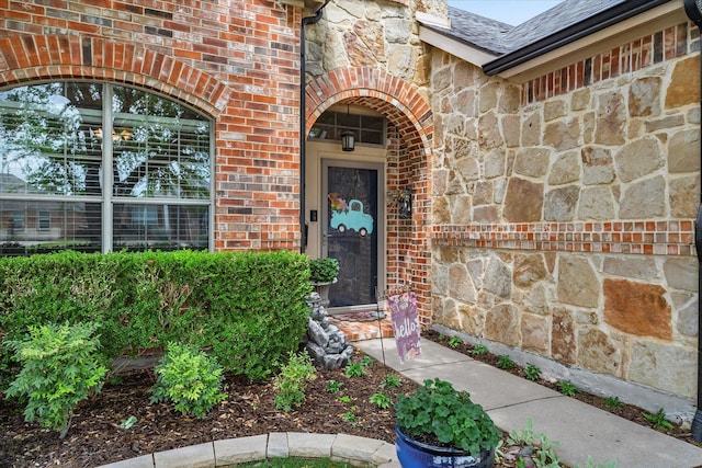 547 Reed Dr, Fate, TX 75087 - view of exterior entry with stone siding, brick siding, and roof with shingles