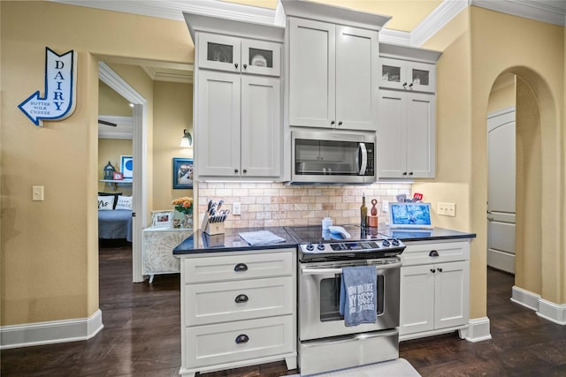 kitchen with backsplash, dark countertops, baseboards, and stainless steel appliances