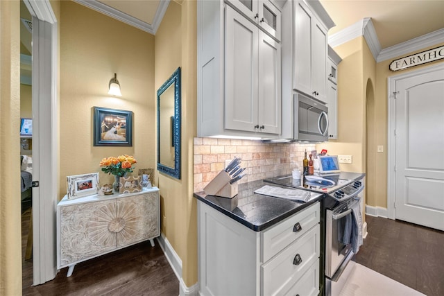 kitchen with dark wood-style flooring, tasteful backsplash, appliances with stainless steel finishes, and crown molding