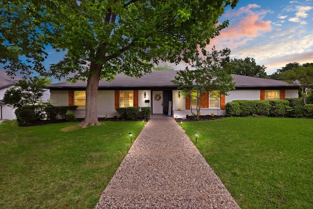ranch-style home with a lawn and brick siding