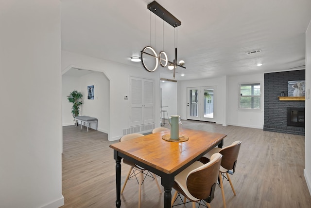 dining room with baseboards, a fireplace, wood finished floors, and a chandelier