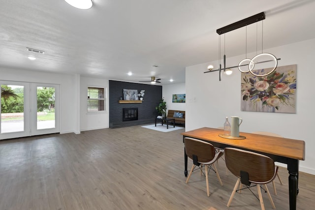 dining space featuring visible vents, wood finished floors, a fireplace, baseboards, and ceiling fan