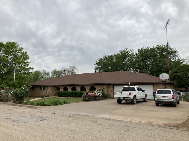 single story home featuring concrete driveway, an attached garage, brick siding, and roof with shingles