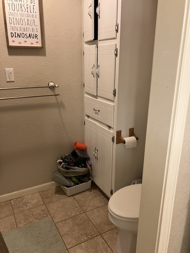 bathroom featuring baseboards, tile patterned flooring, and toilet