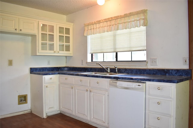 kitchen featuring dark countertops, a sink, white dishwasher, a textured ceiling, and white cabinetry