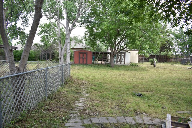4912 Williford Rd, Sachse, TX 75048 - view of yard featuring a storage unit, a fenced backyard, and an outbuilding