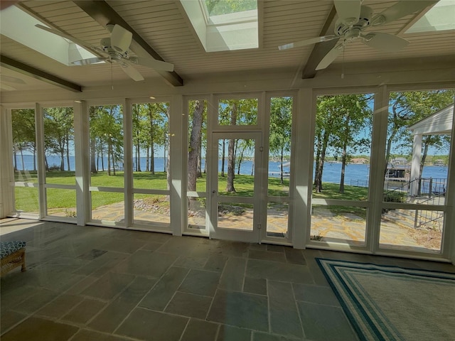 unfurnished sunroom featuring a ceiling fan and a water view