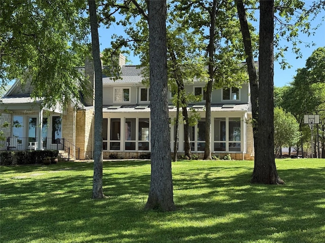 back of house with a chimney, a sunroom, and a yard