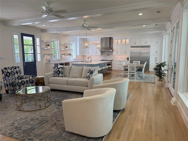 living room featuring a wealth of natural light, ornamental molding, and light wood-type flooring