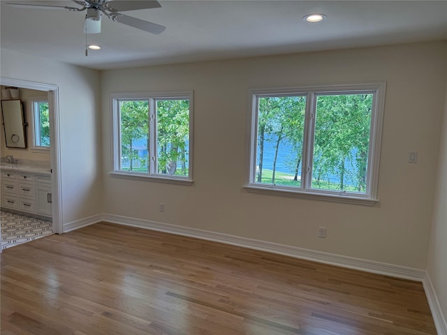 spare room featuring a ceiling fan, baseboards, a healthy amount of sunlight, and light wood-style floors