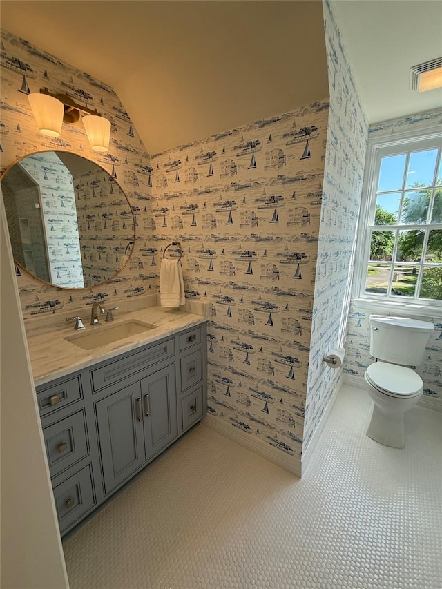 bathroom featuring wallpapered walls, vaulted ceiling, visible vents, and vanity