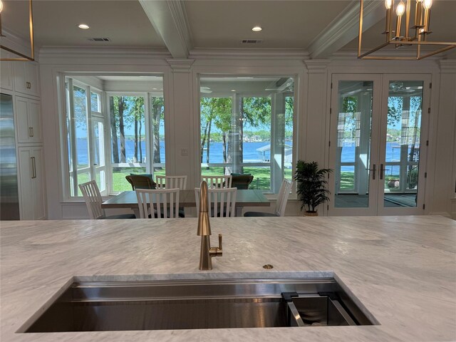 interior space with a chandelier, french doors, light countertops, ornamental molding, and visible vents