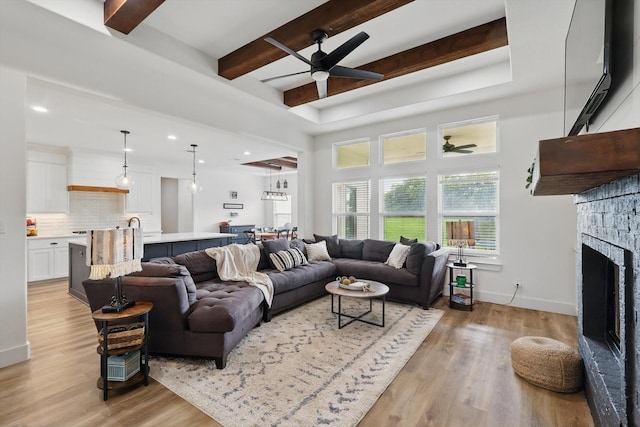 3728 George Owens Rd, Ponder, TX 76259 - living area featuring a ceiling fan, light wood-style flooring, a stone fireplace, beamed ceiling, and baseboards