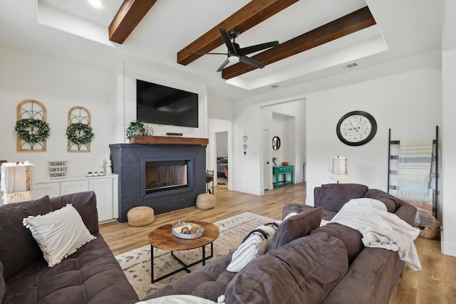 3728 George Owens Rd, Ponder, TX 76259 - living area featuring ceiling fan, a tray ceiling, light wood finished floors, a fireplace, and beamed ceiling