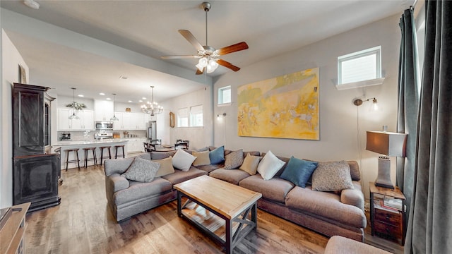 living room featuring ceiling fan with notable chandelier, plenty of natural light, wood finished floors, and recessed lighting