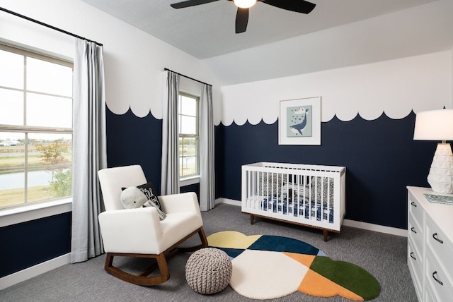 bedroom featuring a crib, carpet flooring, vaulted ceiling, and baseboards