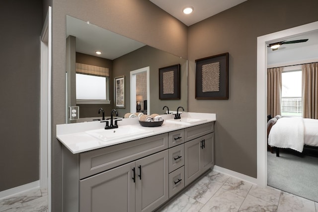 ensuite bathroom featuring baseboards, ensuite bath, marble finish floor, and a sink