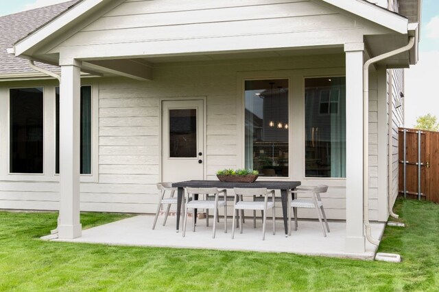 back of house with fence, a patio area, a yard, and a shingled roof
