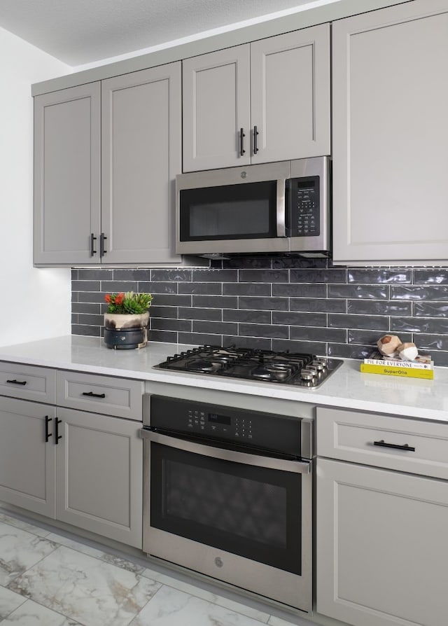kitchen with marble finish floor, gray cabinets, stainless steel appliances, and light countertops