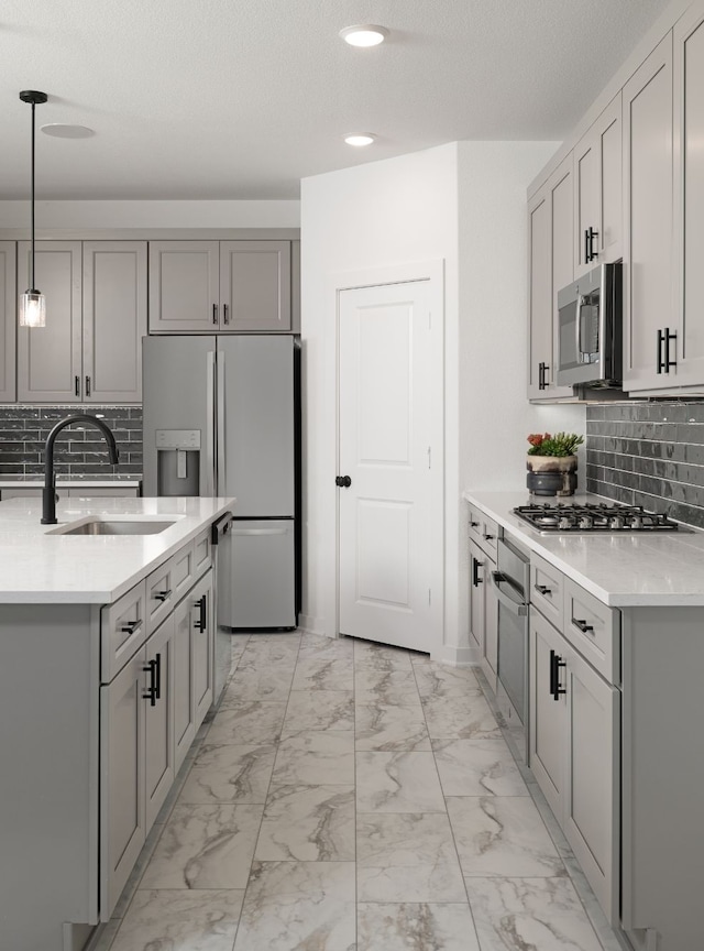 kitchen with a sink, stainless steel appliances, decorative backsplash, marble finish floor, and gray cabinetry