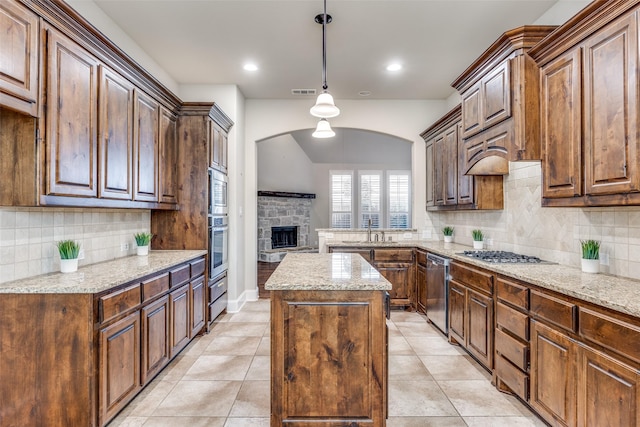 kitchen with arched walkways, light stone countertops, a kitchen island, and decorative backsplash