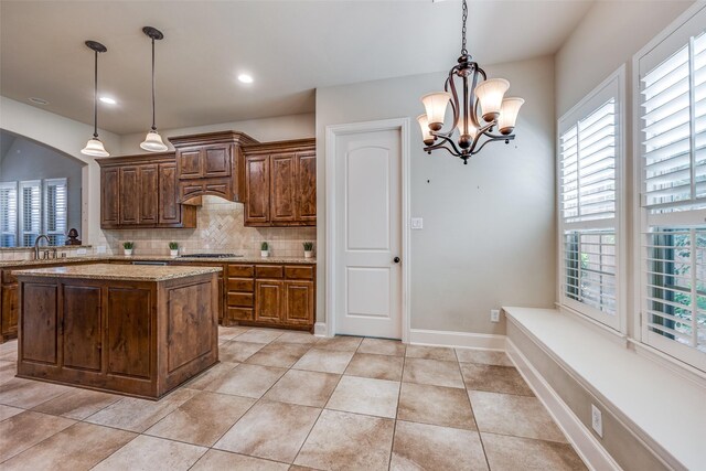 kitchen featuring stainless steel gas stovetop, a healthy amount of sunlight, a notable chandelier, and tasteful backsplash