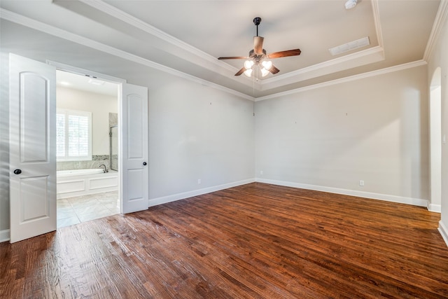 spare room featuring a ceiling fan, wood finished floors, a raised ceiling, ornamental molding, and visible vents