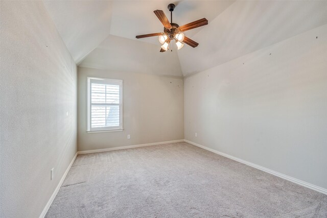 empty room featuring ceiling fan, light carpet, vaulted ceiling, and baseboards
