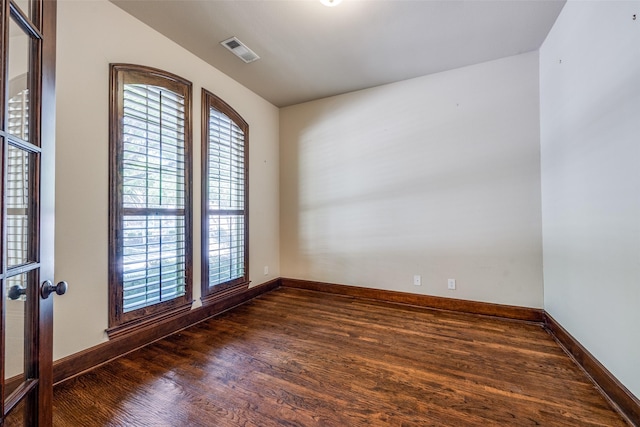 empty room featuring baseboards, wood finished floors, visible vents, and a wealth of natural light